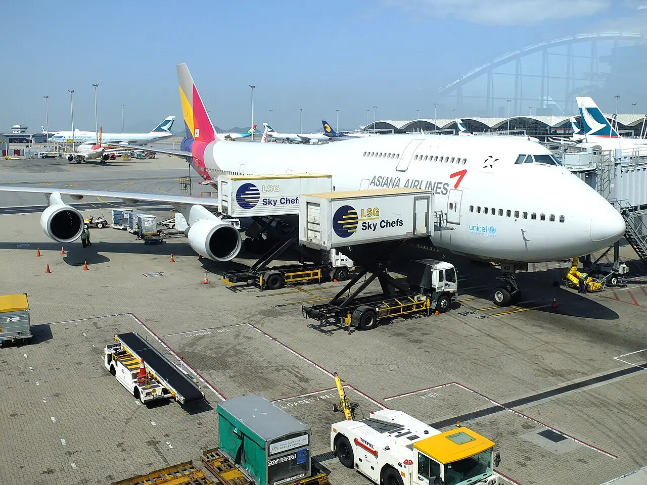 Catering trucks raise their boxes to the doors of a passenger plane.