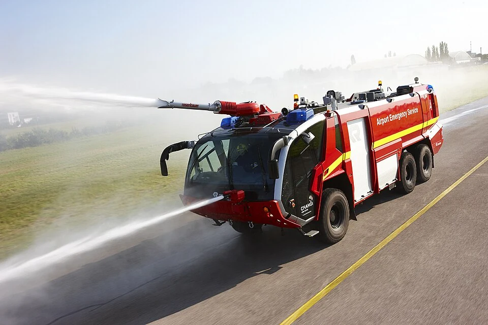 A red airport fire engine sprays water from its front.