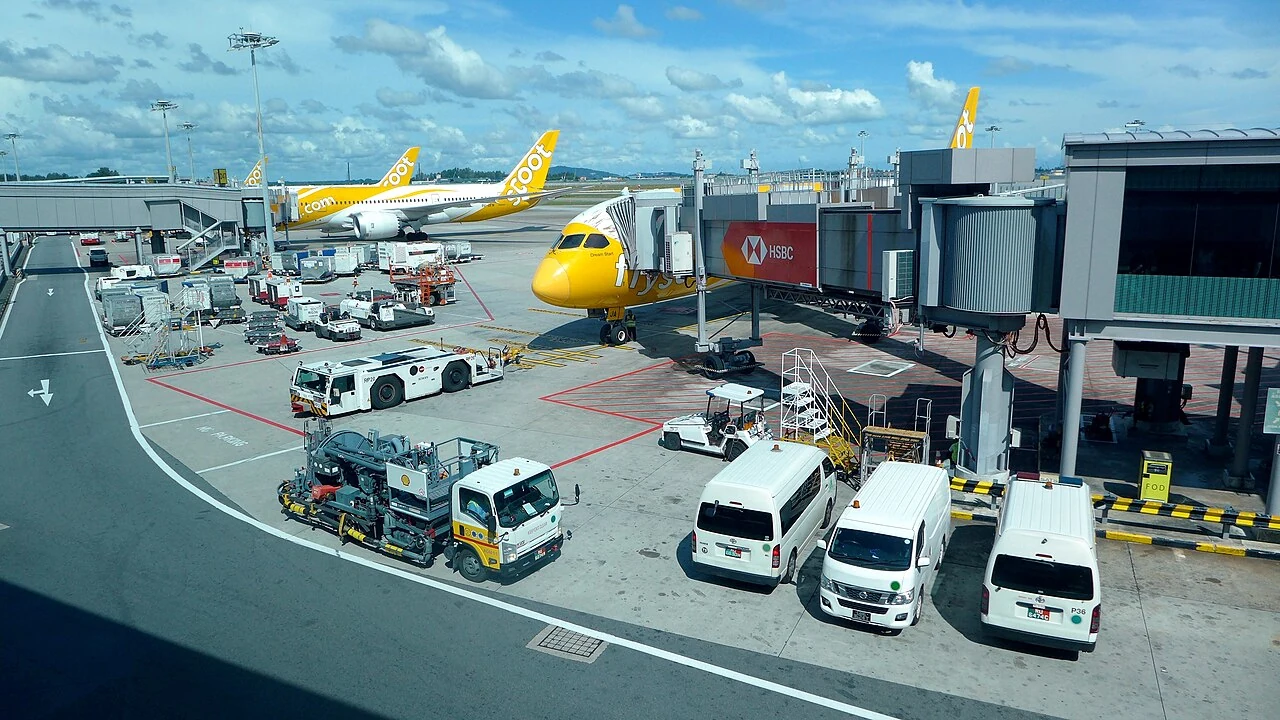 A large airport fuel dispenser has hoses and delivery equipment beside an aircraft stand.