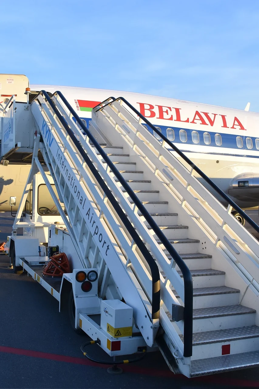 A wheeled stairway has metal steps between tall white side panels.