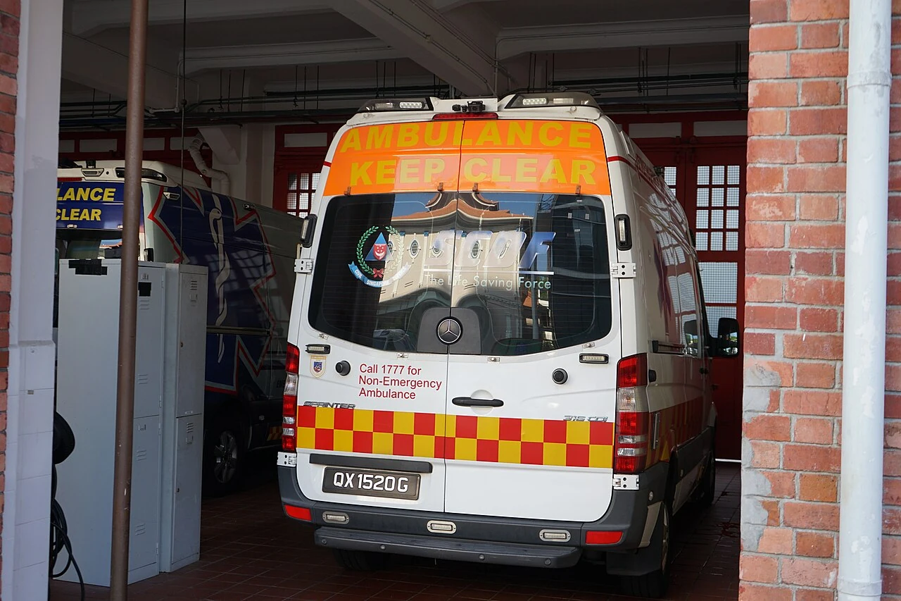 The rear of a white ambulance has red-and-yellow checks inside a garage doorway.