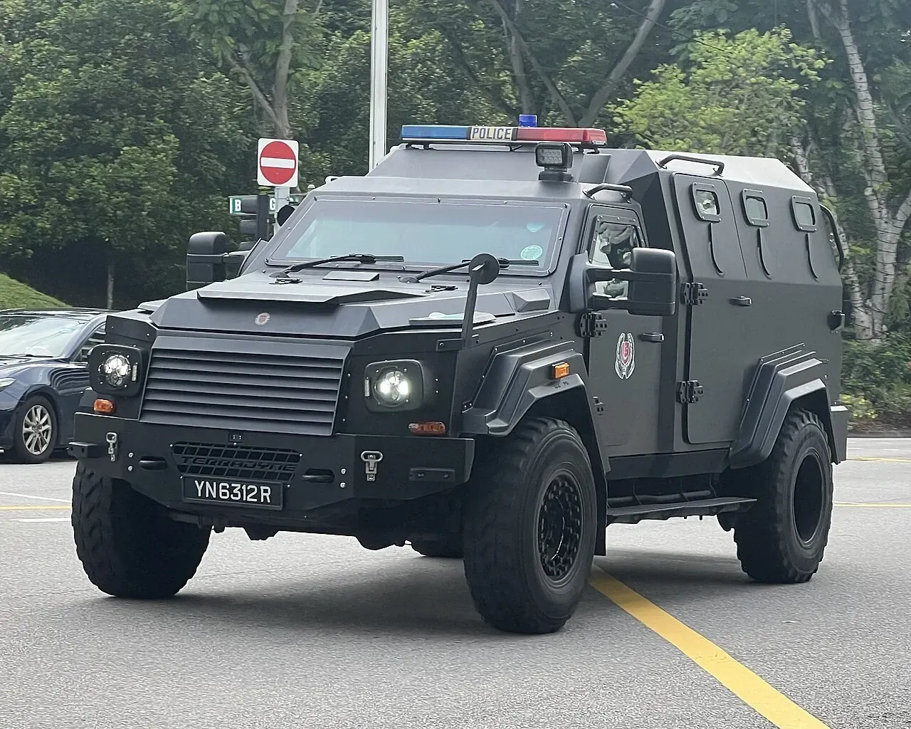 A dark armoured Singapore Police vehicle on a road.