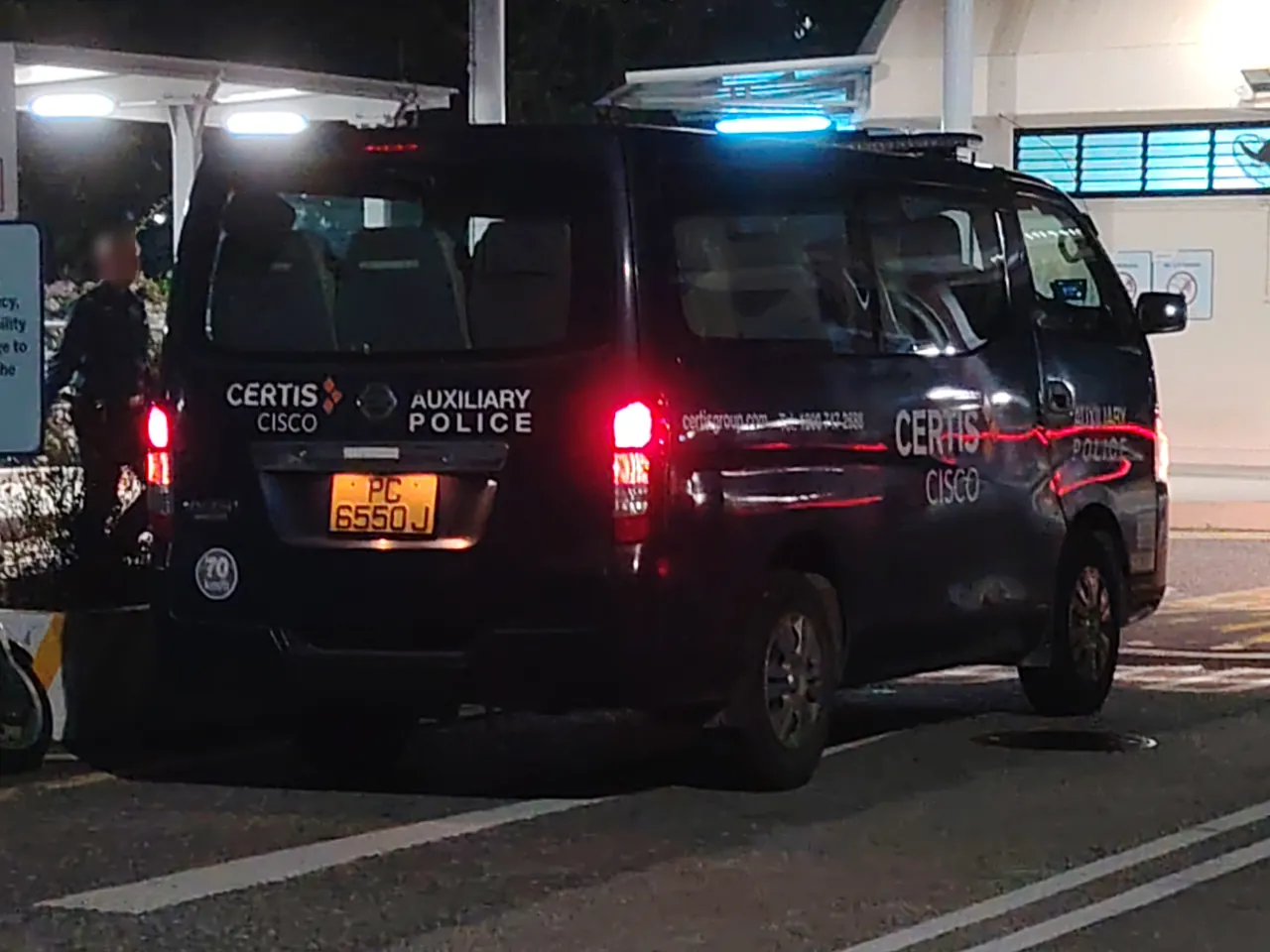 Auxiliary police van — a dark blue auxiliary police van at night with a blue light on top.