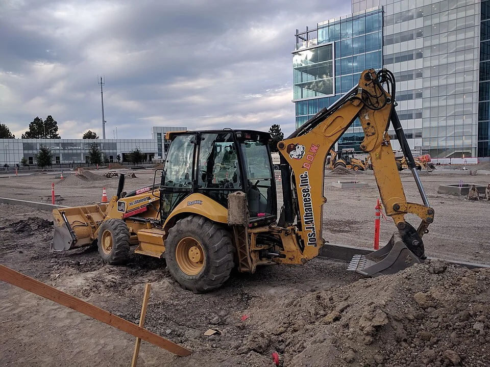 A yellow backhoe loader has a front bucket and a digging arm at the back.