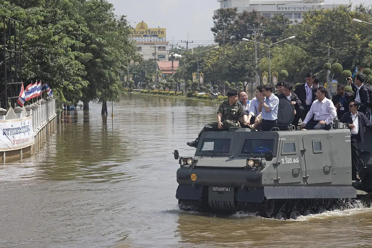 A Bronco tracked carrier moves through floodwater with people on top.