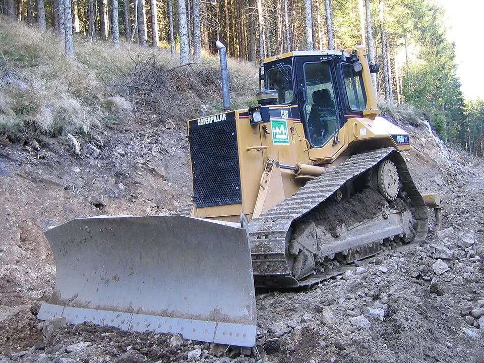 A yellow bulldozer has metal tracks and a broad grey blade at the front.