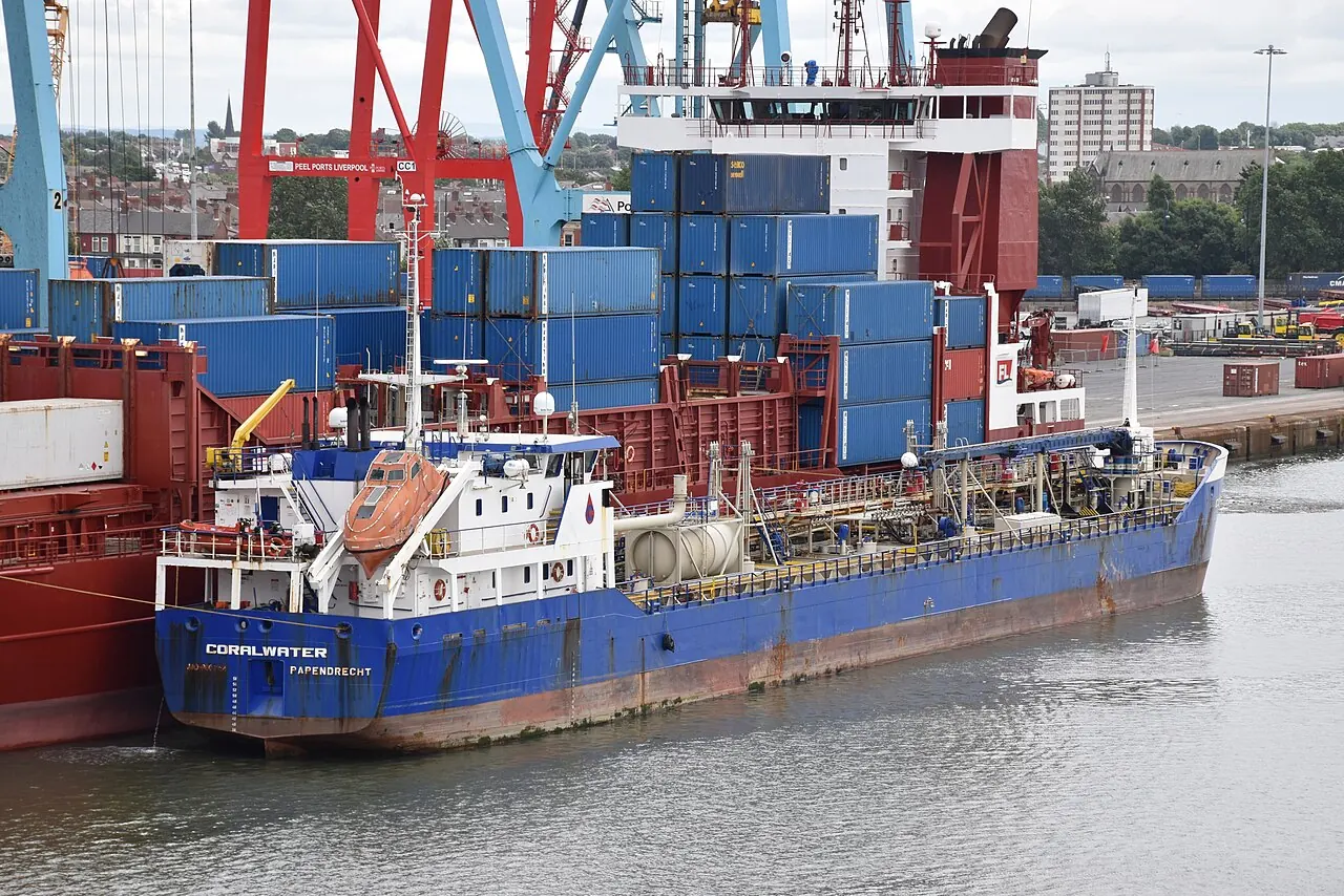The blue bunker barge Coralwater lies beside a much larger container ship.