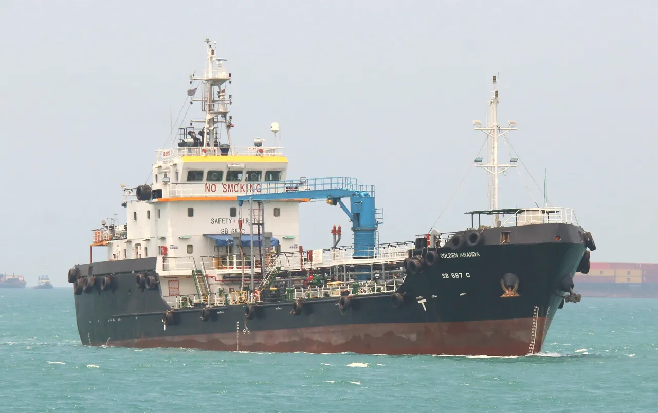 A black bunker vessel has a tall cream-coloured bridge and pipes along its deck.