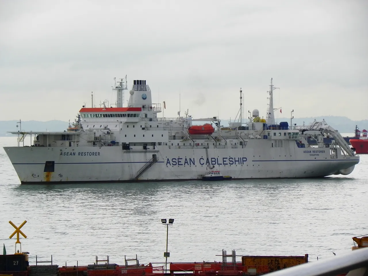 A white cable ship has several decks of windows and ASEAN CABLESHIP written on its side.
