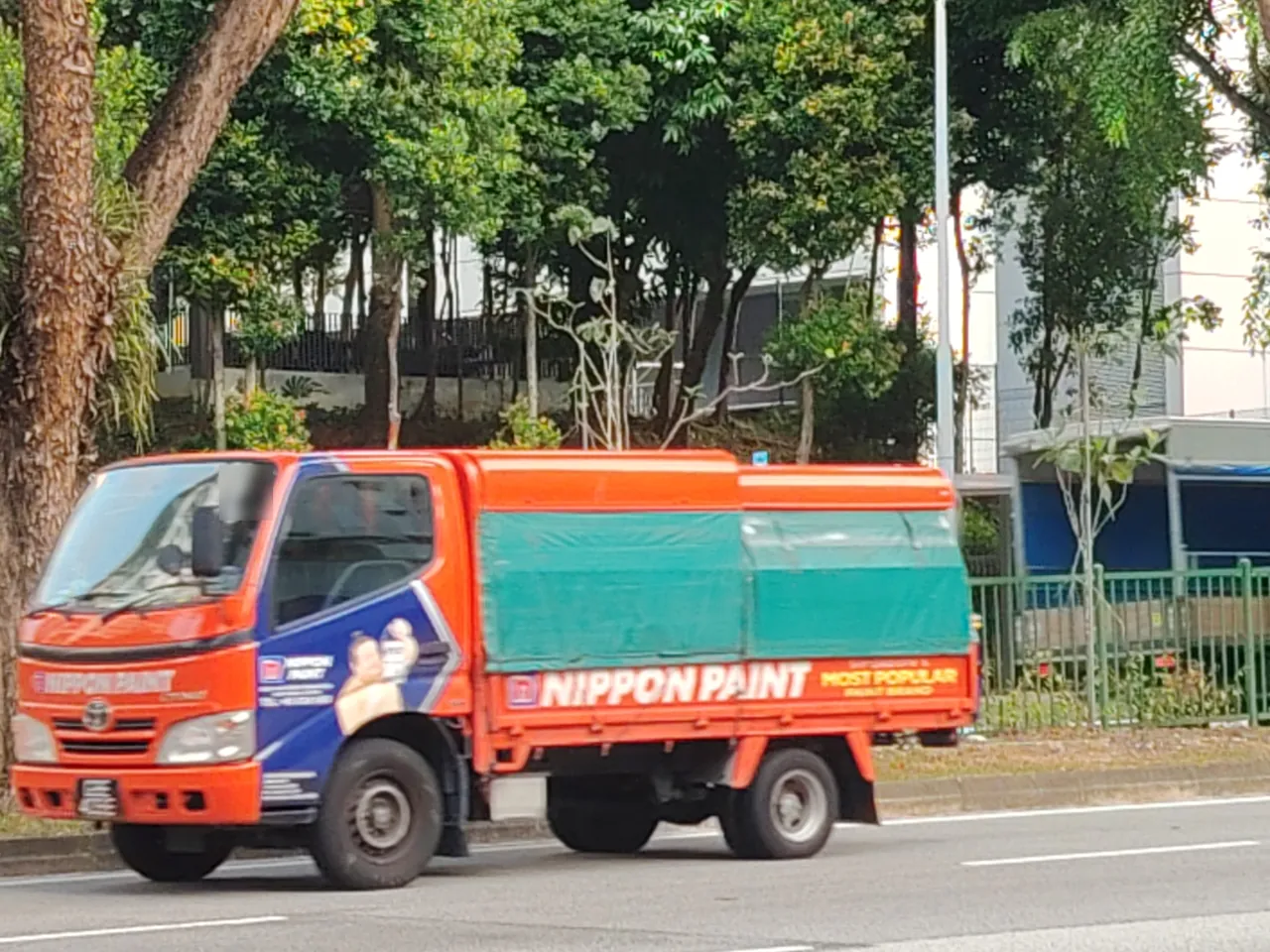 Canopy lorry — an orange lorry with a green cover pulled over its load.
