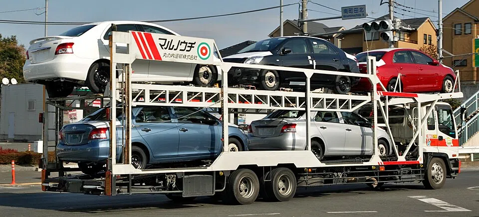 A white car transporter carries cars on two open decks.