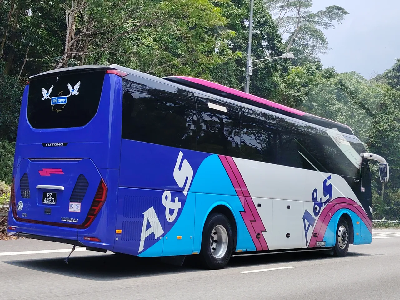 Coach — a blue, light blue, pink and white coach seen from behind on a road, Photographed in Singapore