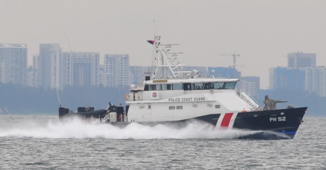 A white police boat with red-and-blue markings throws up spray as it moves.