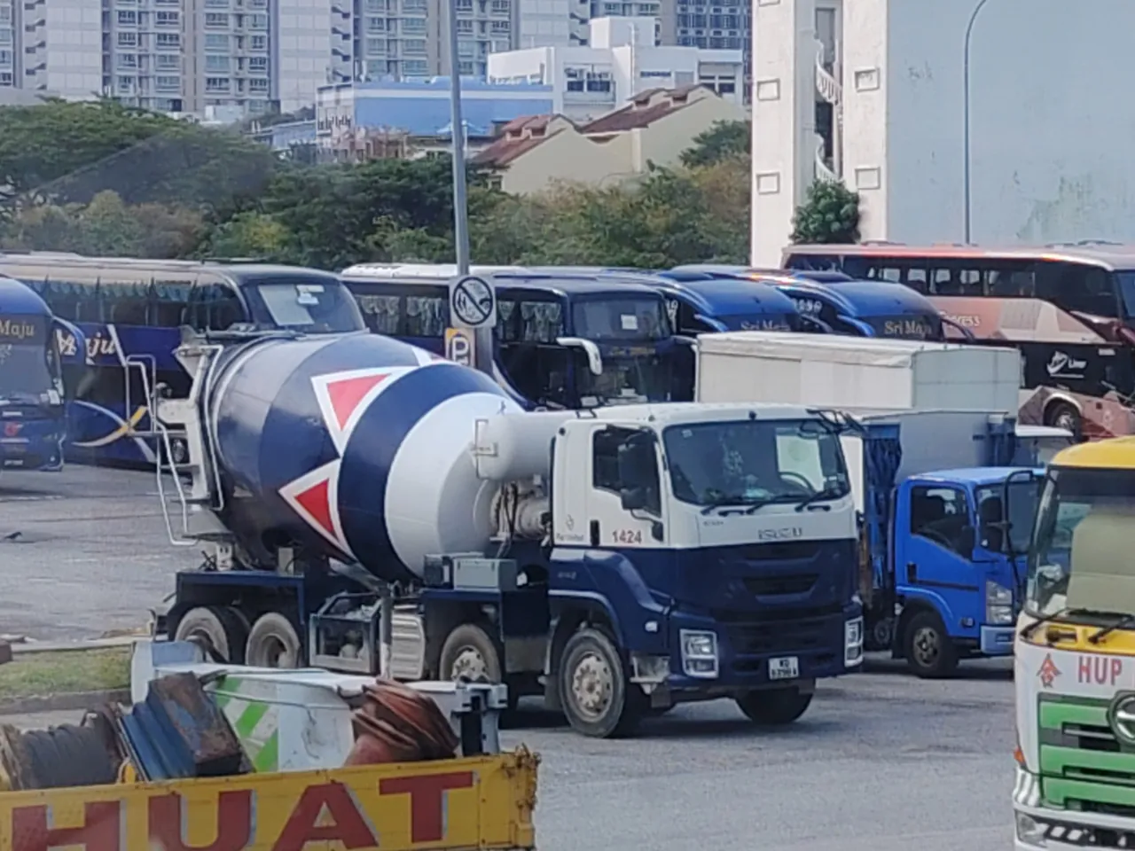 A white mixer truck has a large drum painted with red and blue bands.