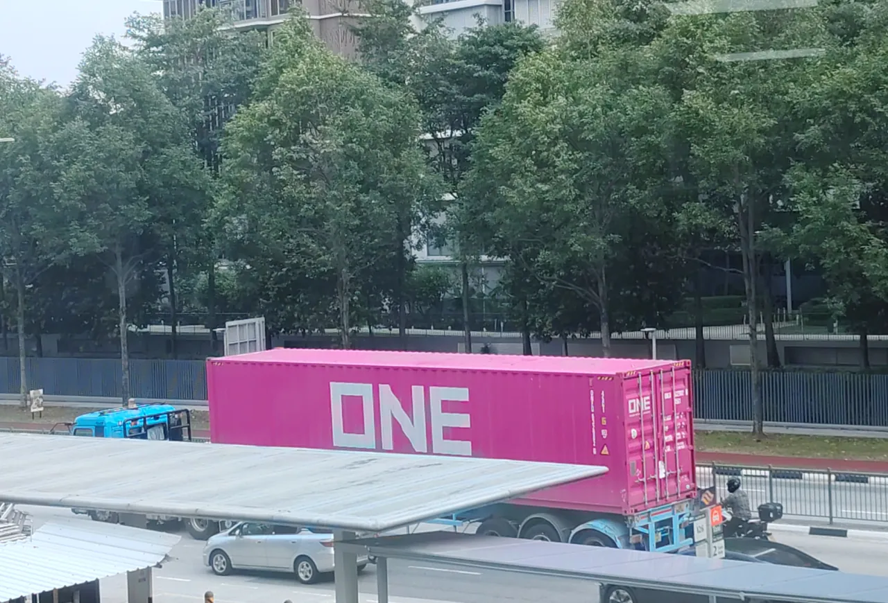 Container truck — a bright pink shipping container on a trailer, photographed in Singapore.