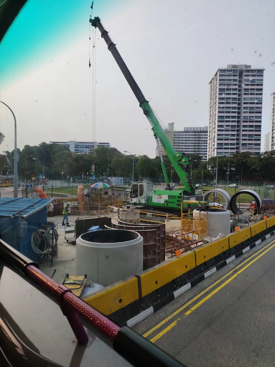 Crawler crane — a green crawler crane with its boom raised over a worksite, photographed in Singapore