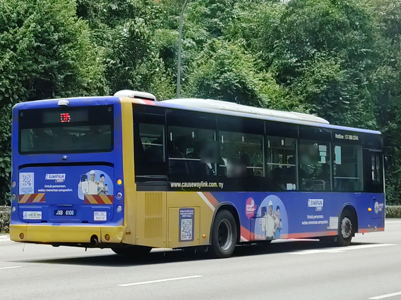 Cross-border bus — a blue and yellow single-deck bus seen from behind on a road, Photographed in Singapore