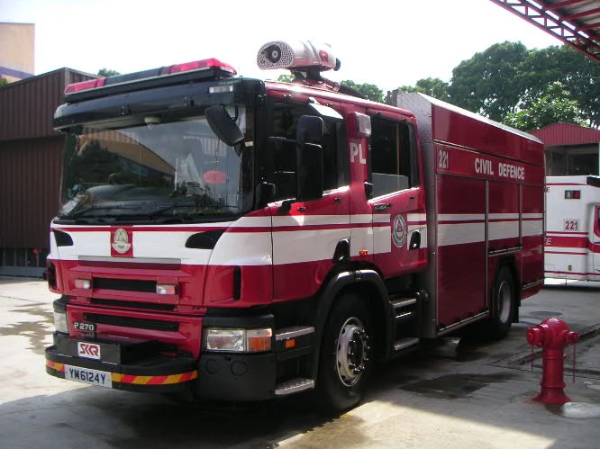 A red fire engine with a white stripe is parked beside a red fire hydrant.