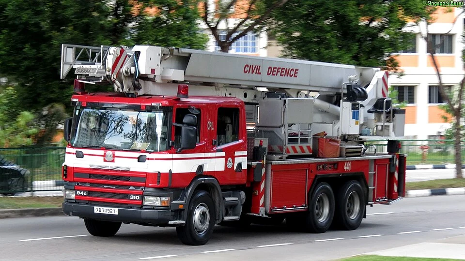 A red fire truck carries a long ladder above its cab.