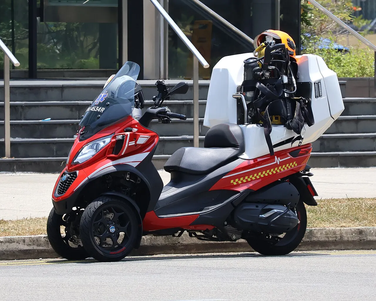 A red fire bike carries white equipment boxes behind its seat.