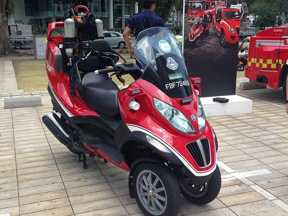 A red three-wheeled fire motorcycle has a black seat and a tall windscreen.