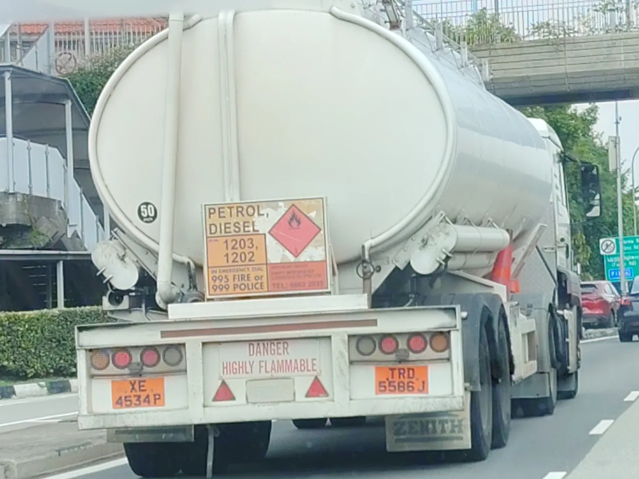 Fuel tanker — the back of a white petrol and diesel tanker with an orange hazard sign and a faded red flame diamond, Photographed in Singapore