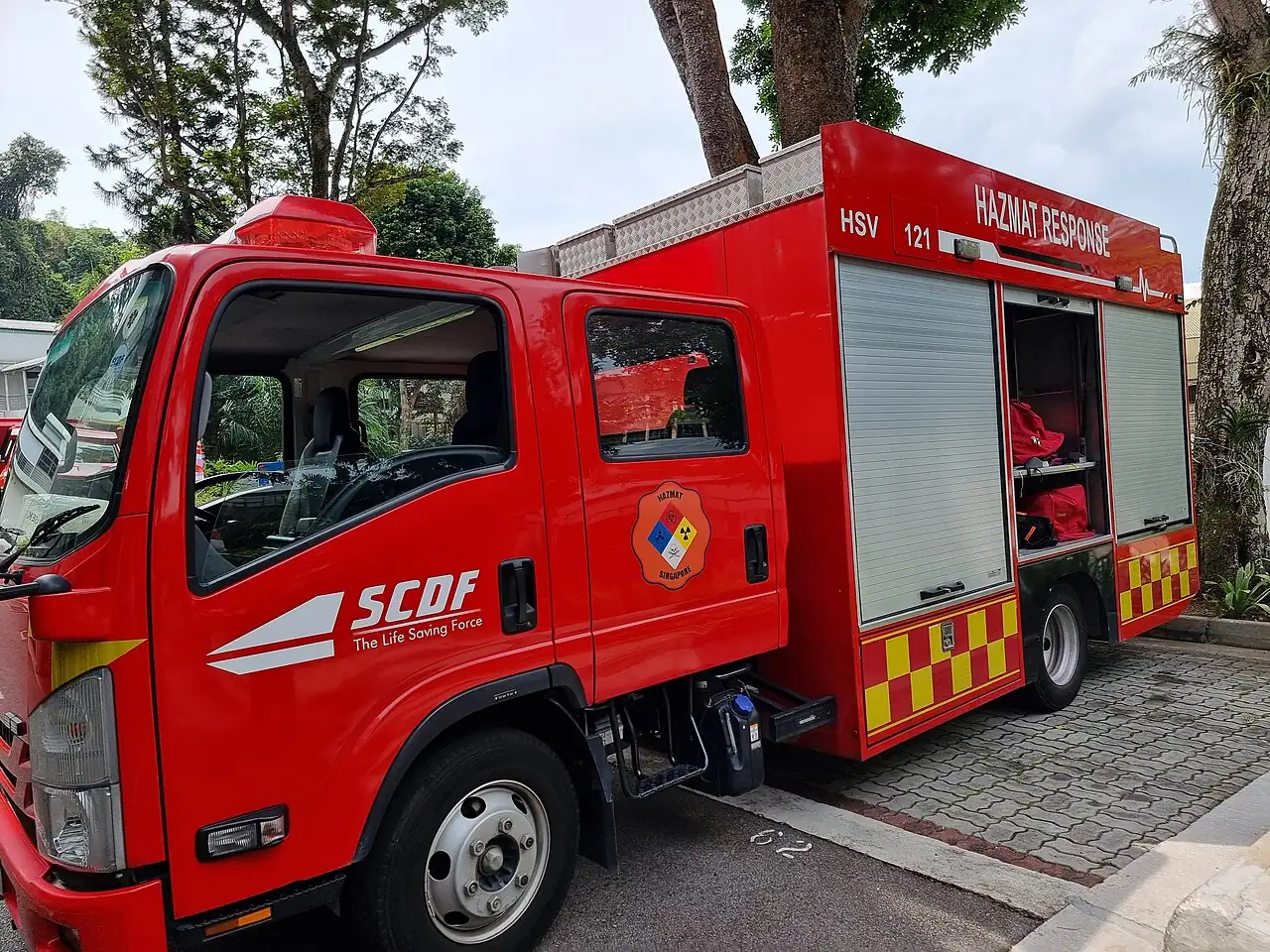 A red hazardous-materials response truck has equipment compartments along its side.