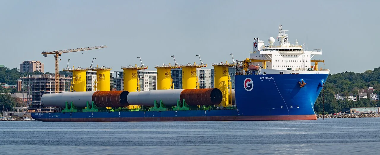 A heavy-lift ship carries large yellow and dark cylinders on its deck.