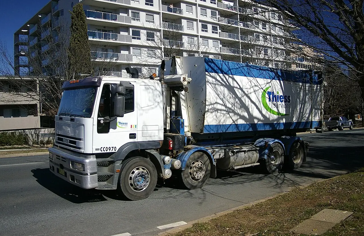 A hooklift truck carrying a large removable waste container in Australia.