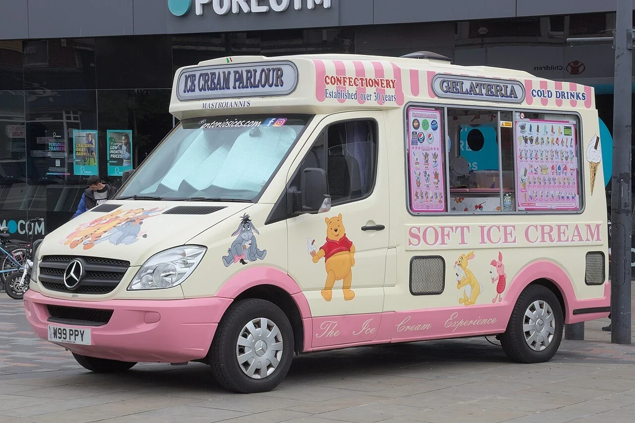 A pink-and-white ice-cream van has pictures of ice creams along its side.