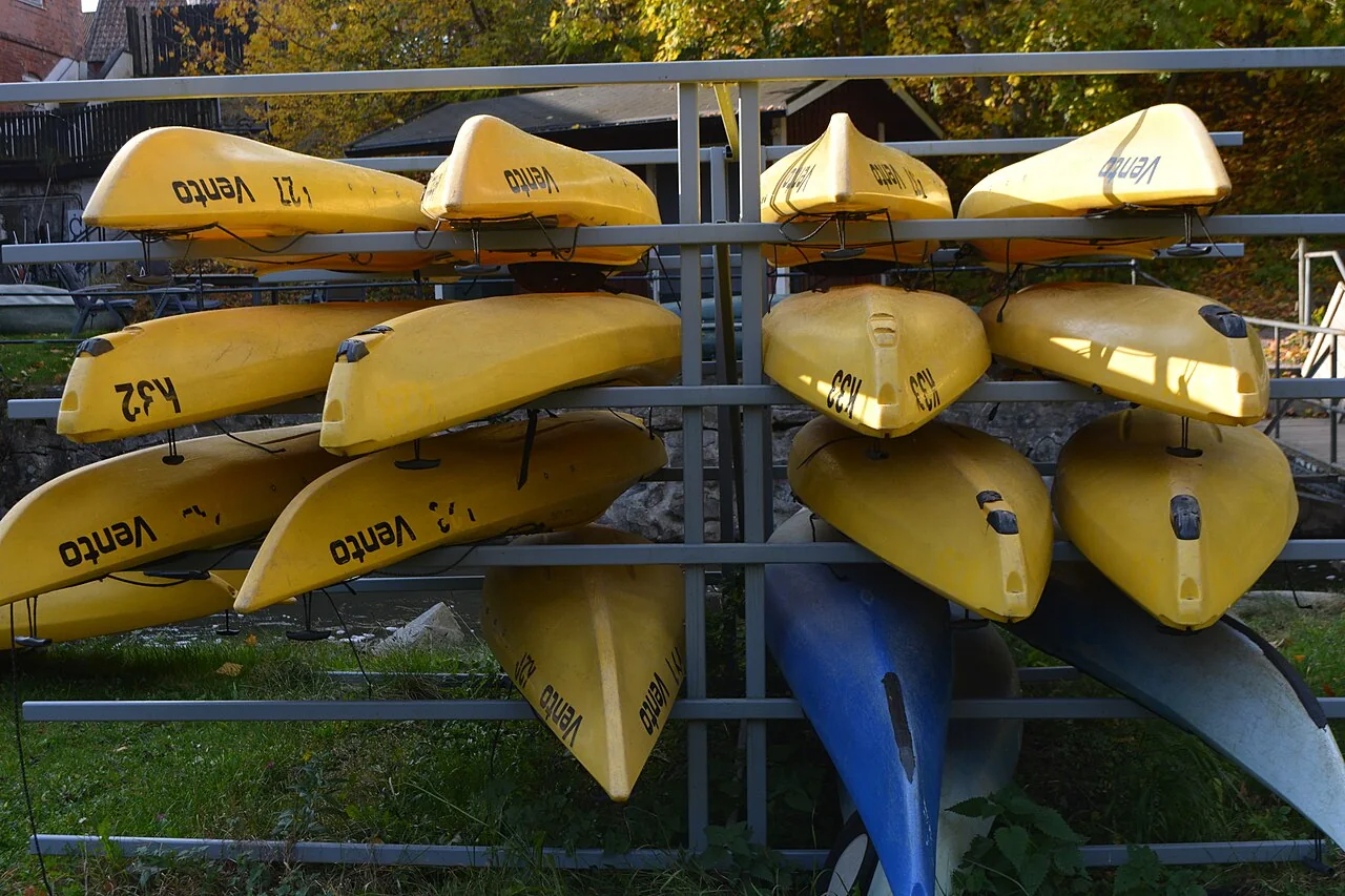 Yellow and blue kayaks rest on racks beside each other.