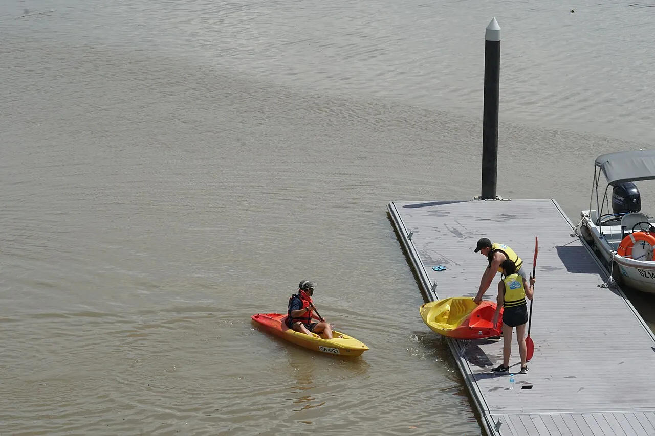 A paddler sits in a bright kayak on the water.
