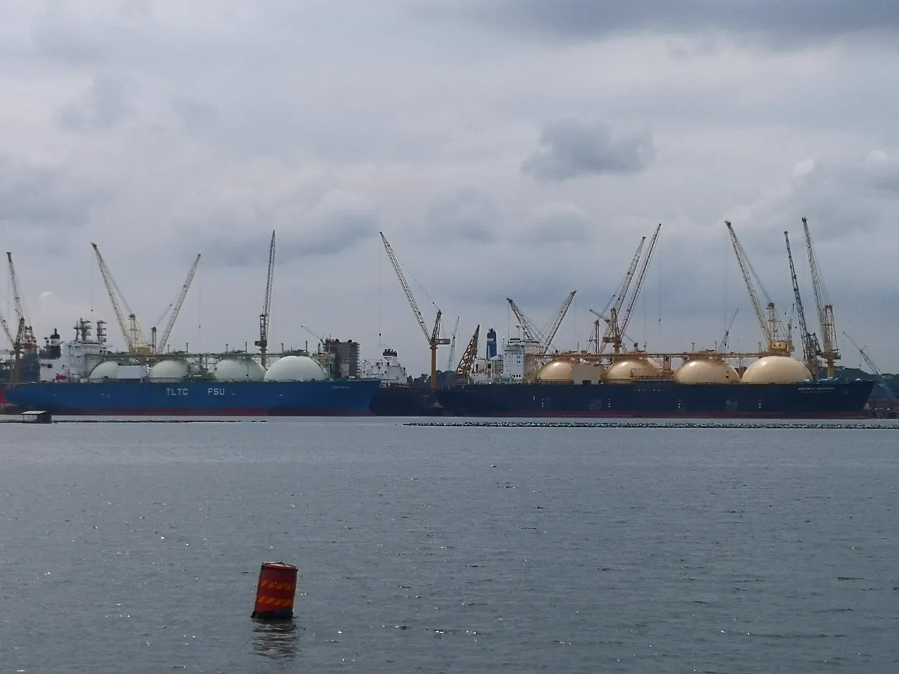 A large blue LNG carrier has several round tanks along its deck.