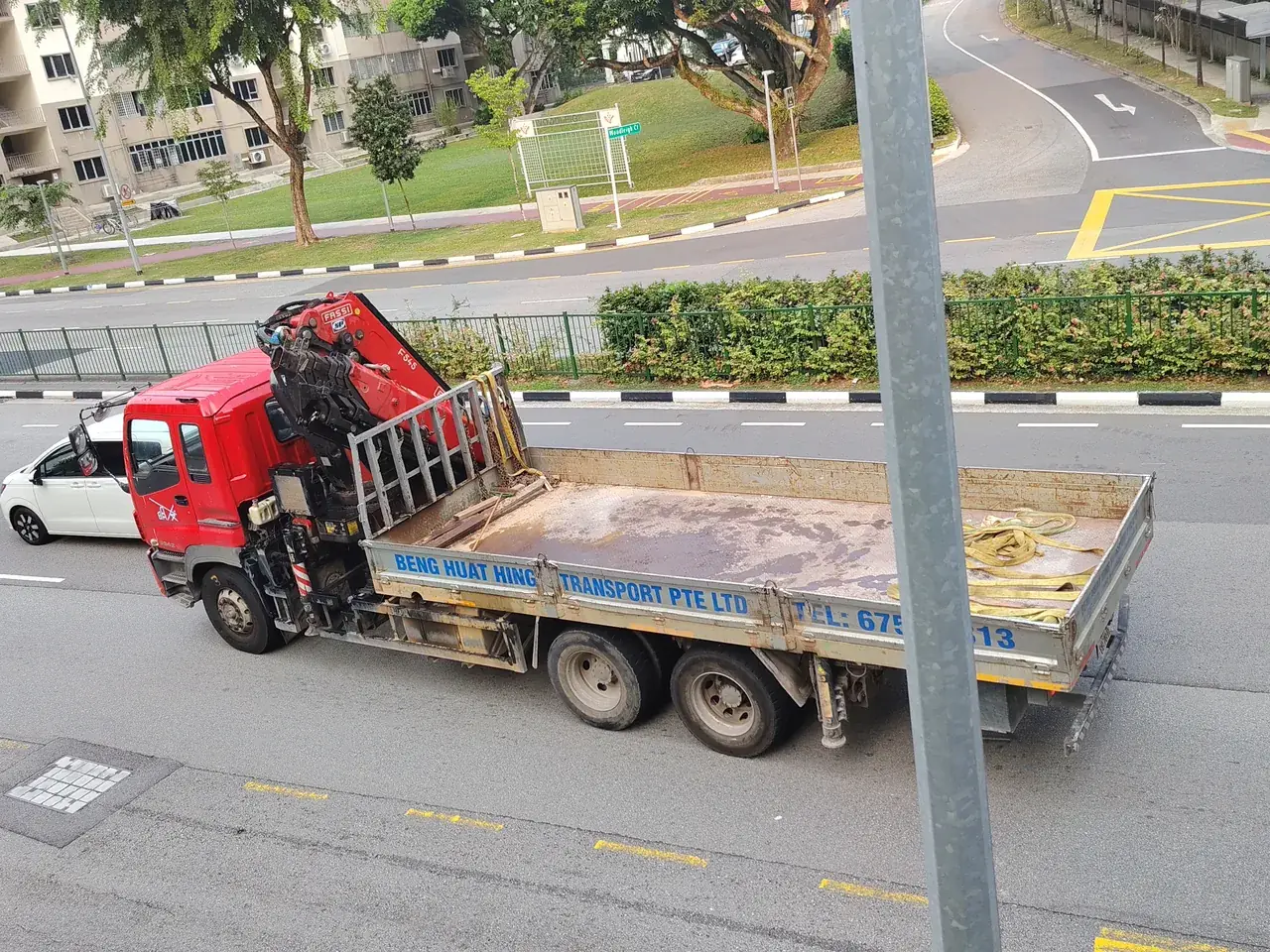 A red lorry crane carries its folded arm on a flatbed.