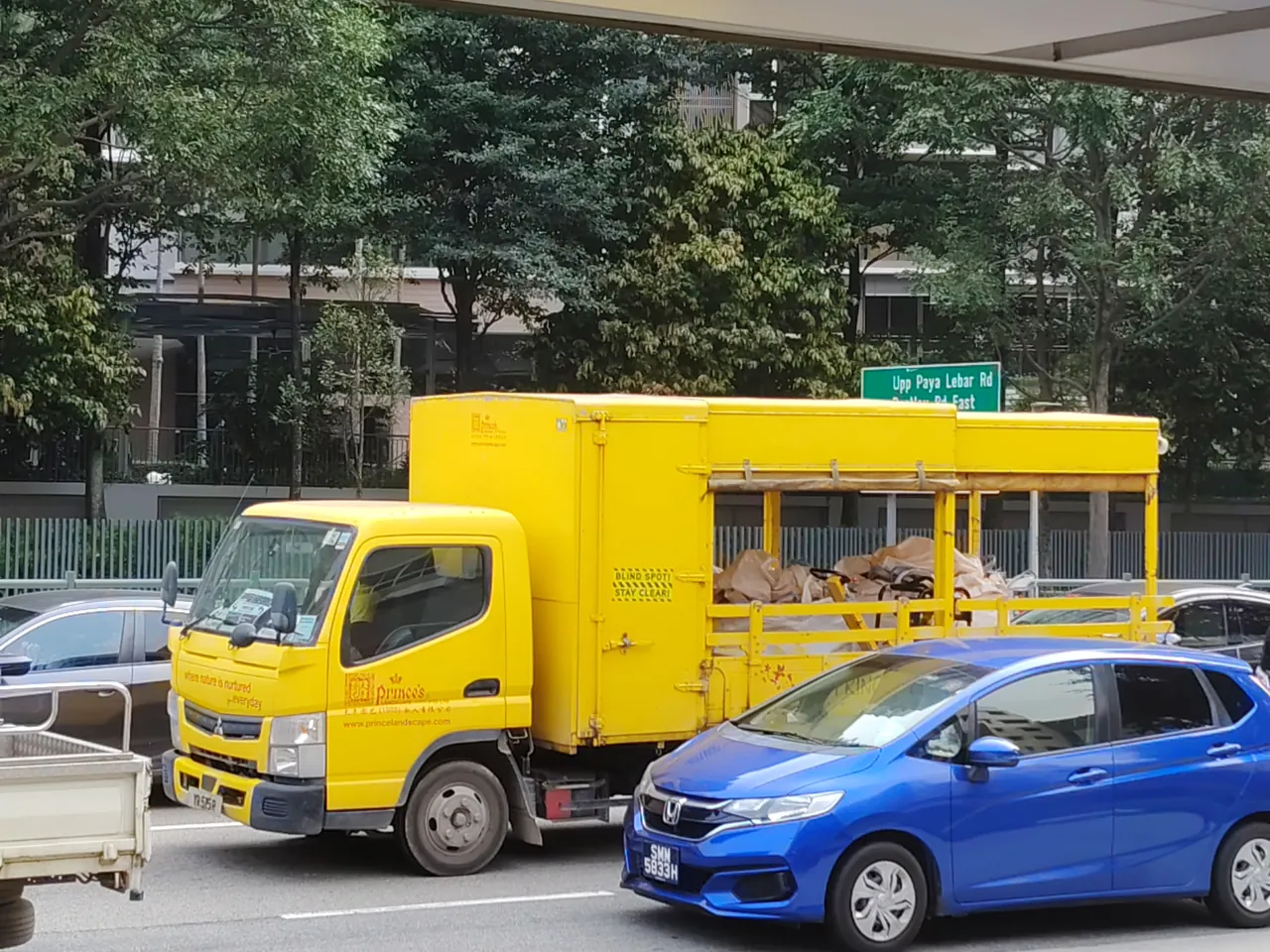 Lorry — a yellow lorry with a box body and an open cargo frame, photographed in Singapore.