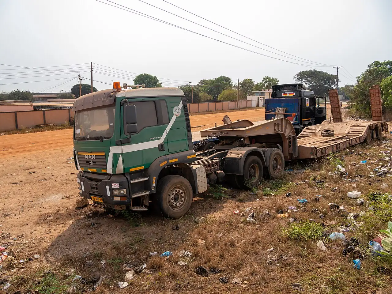 A green truck pulls a long low trailer carrying equipment.