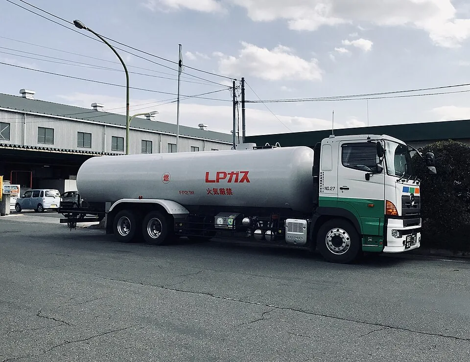 A green-and-white tanker has a long silver tank behind its cab.