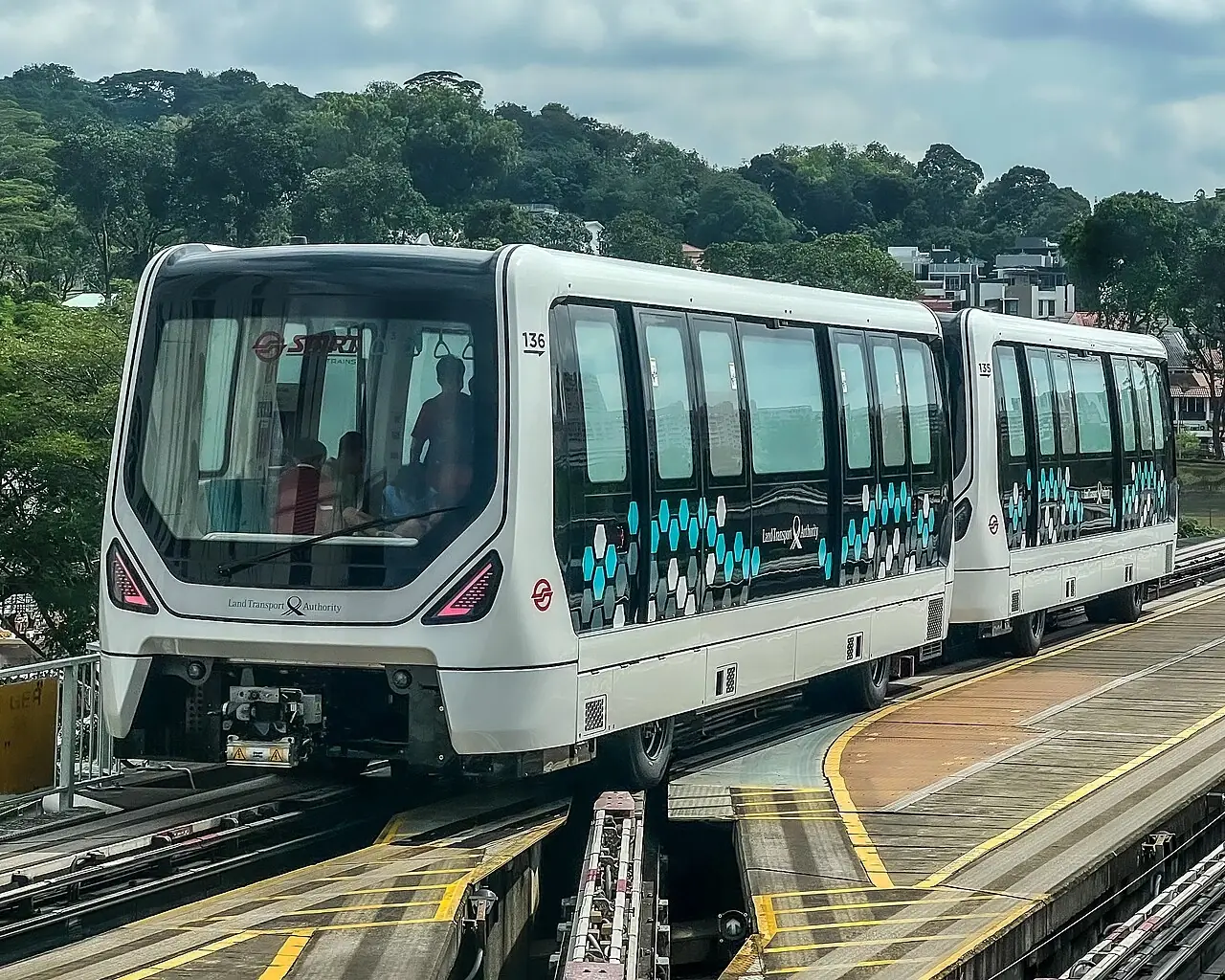 A white LRT train has a wide dark front window and two connected carriages.