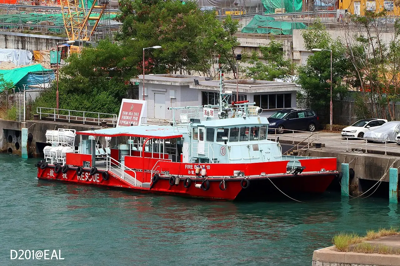 A red fireboat with a white cabin is moored beside a quay.
