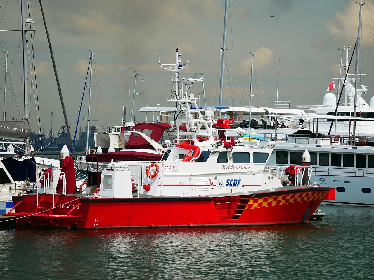 A red-and-white fireboat has yellow checks along its side and water nozzles above the cabin.
