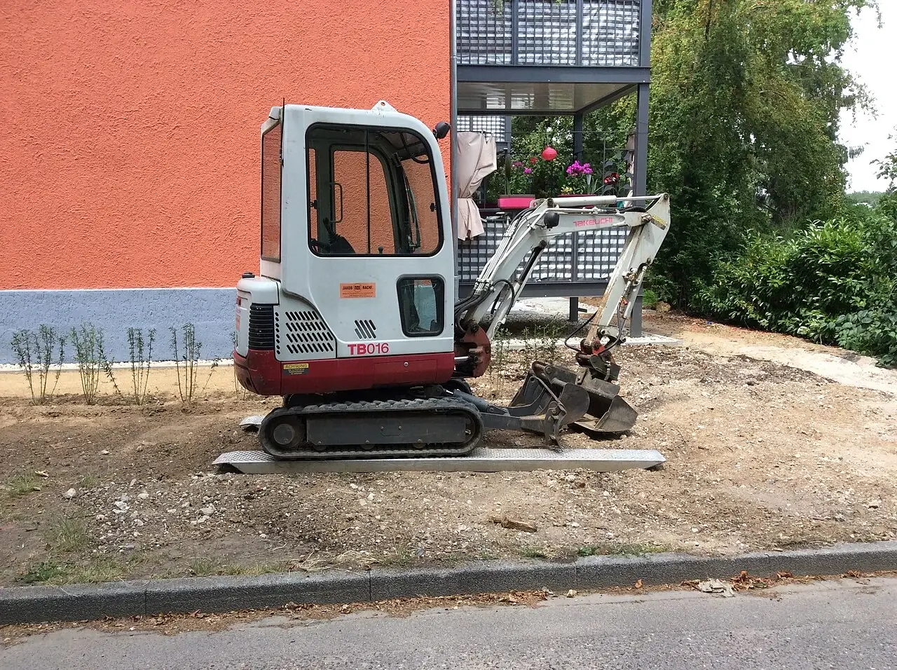 A small white and red tracked excavator with a digging bucket.