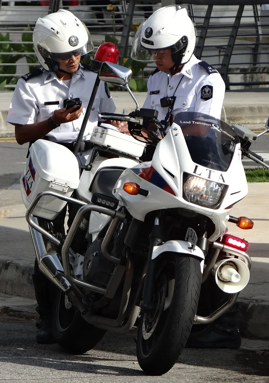 Two helmeted officers stand beside white motorcycles with large windscreens.