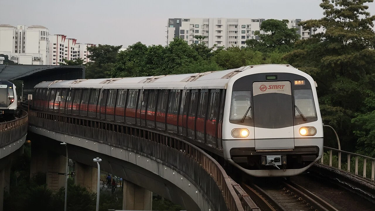 A white MRT train curves along an elevated track, with a dark front window.