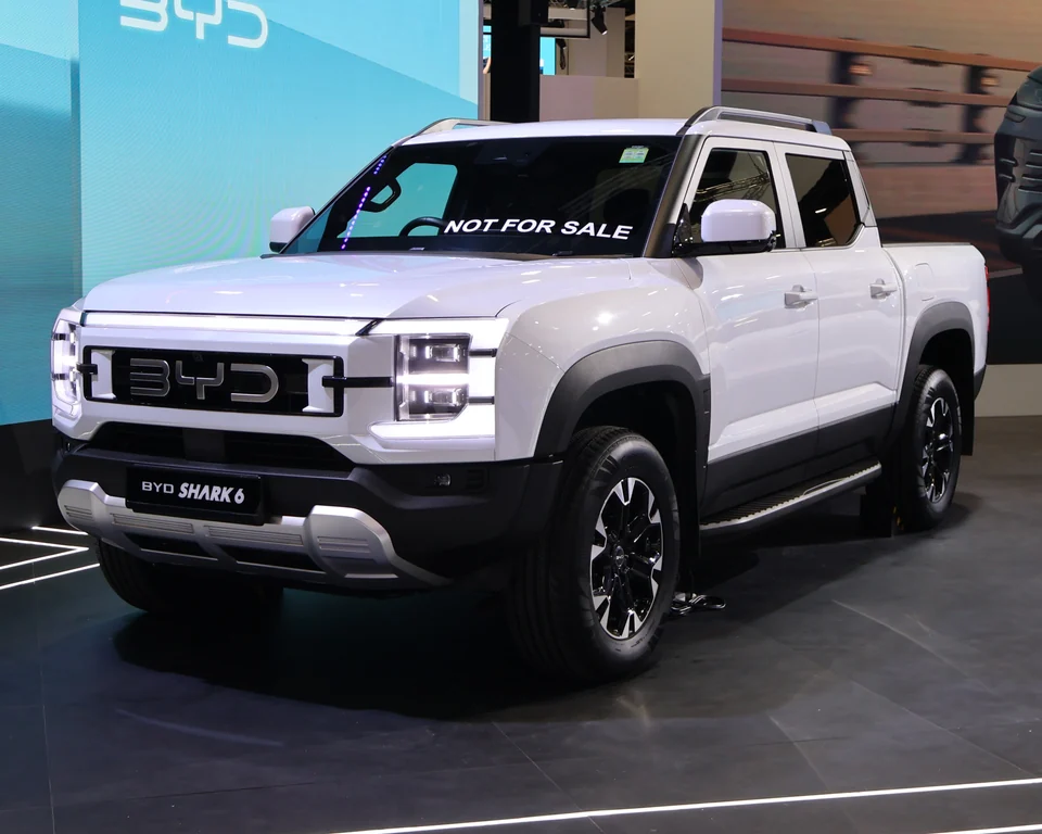 A white pickup with four doors and black wheel arches stands on a display floor.