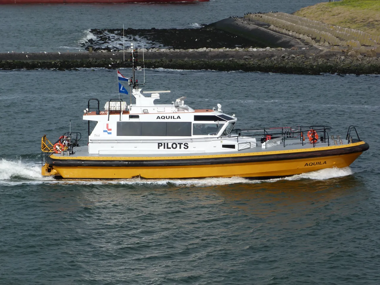 A yellow-hulled pilot boat has a white cabin marked PILOTS.