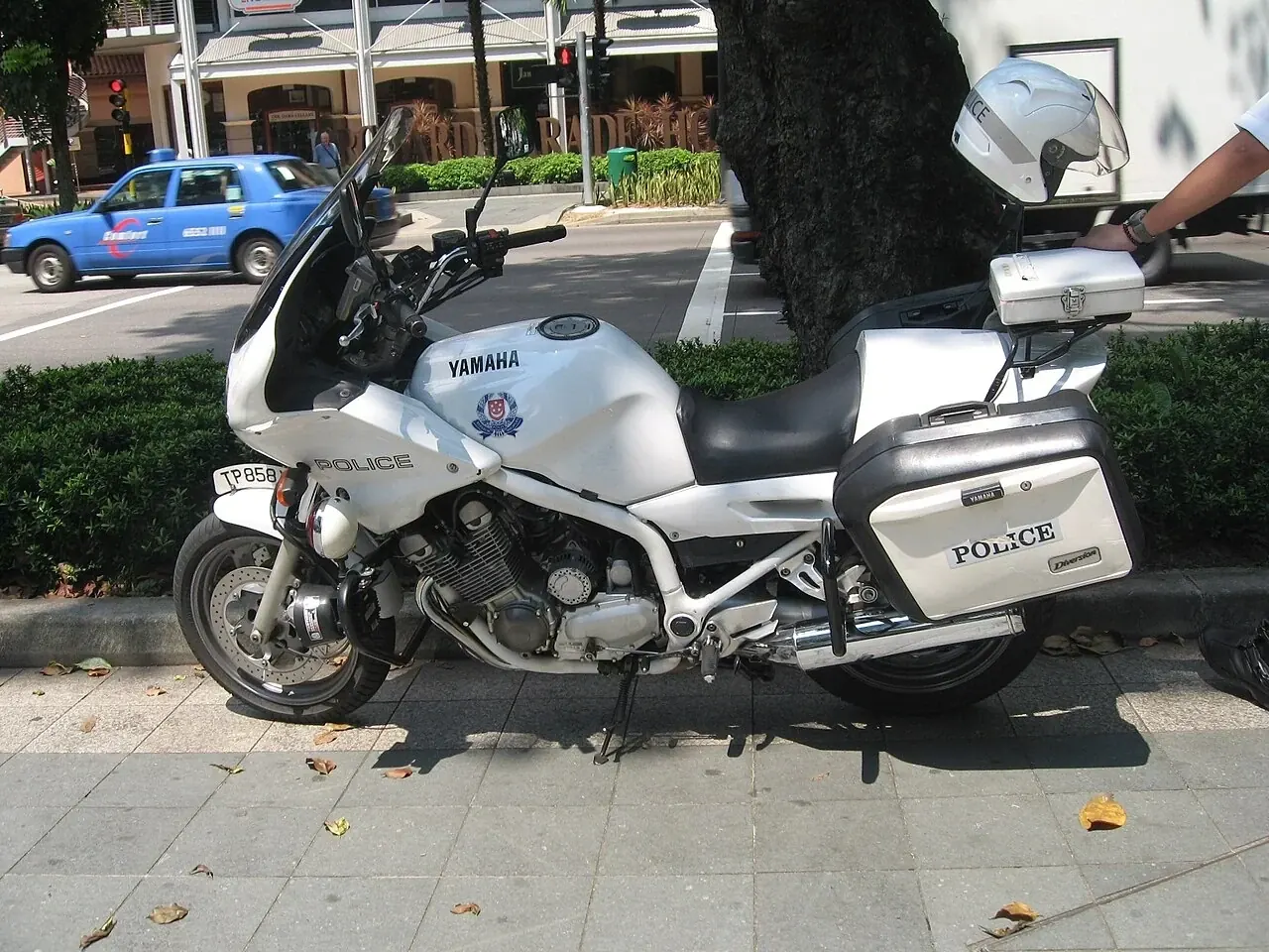 A white police motorcycle has a windscreen and side boxes.