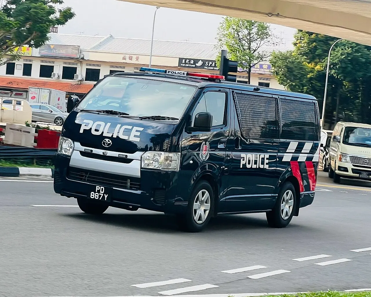 A dark blue police van has red-and-blue markings along its side.