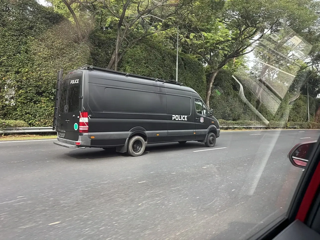 A dark police van has blue lights on its roof.