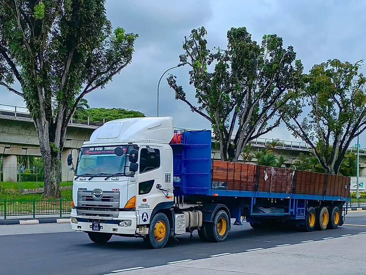 A white prime mover pulling a long blue trailer in Singapore.