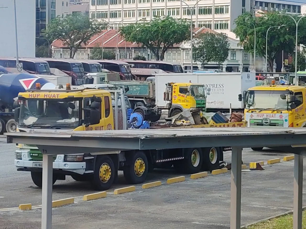 A yellow recovery truck has a long empty flatbed behind its cab.